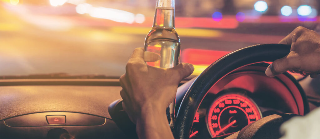 A man drinking and driving on a busy city street