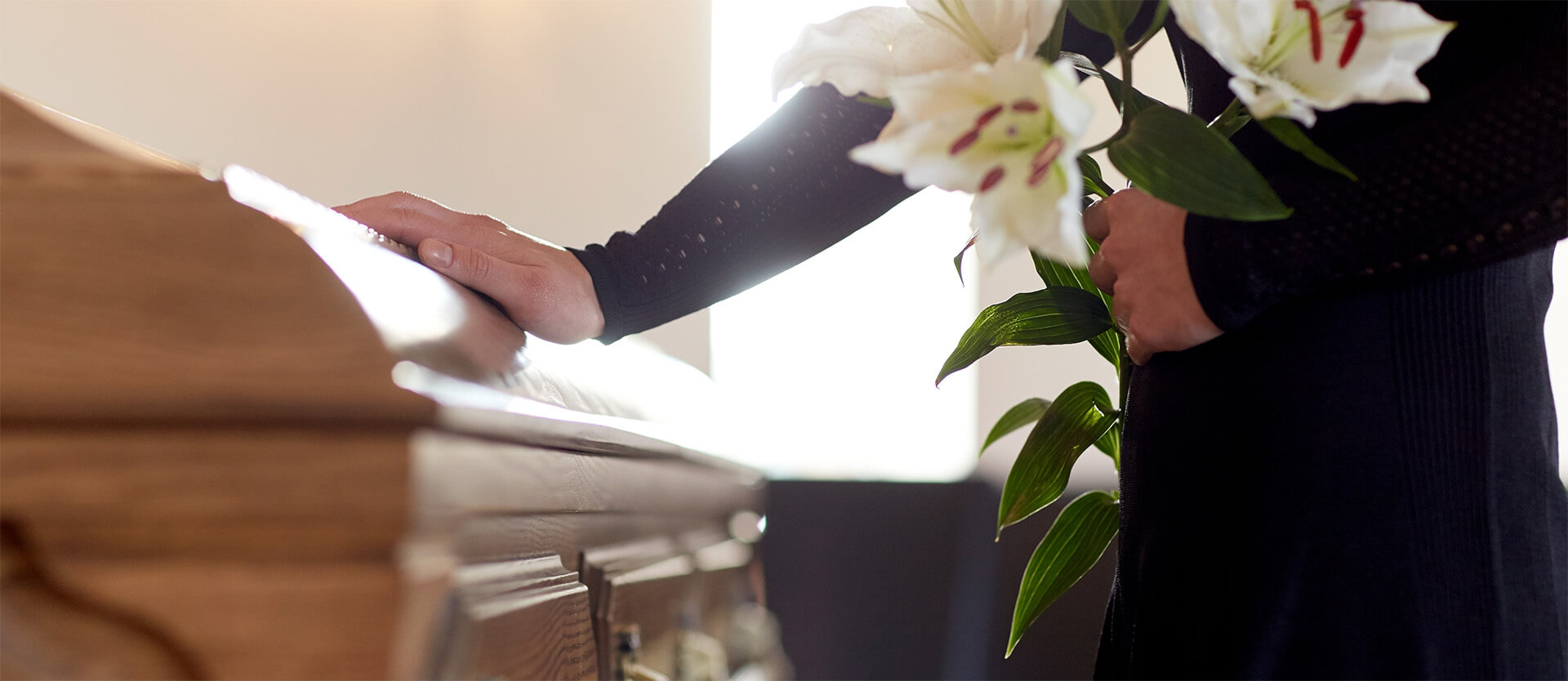 a person putting their hand on a coffin while holding flowers
