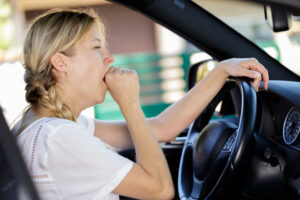 a woman yawning while driving her car fatigued.