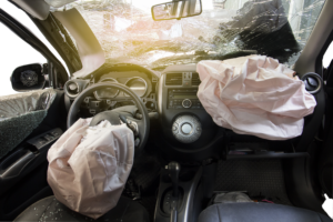 The inside of a car after a major car accident with a broken windshield and the airbags deployed.