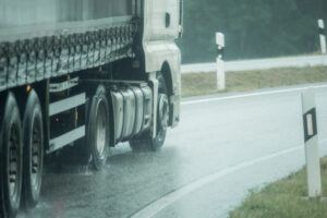A truck is driving on the road in the rain