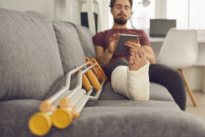 a man with a broken leg on his couch looking at his phone to look up a Nevada Personal injury lawyer